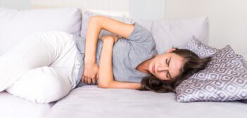 Women have abdominal pain because of menstruation lying in couch and holding her stomach.